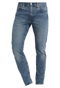 Blå denimjeans, slim fit, med en sliten textur, fem fickor, dragkedja och metallknapp som stängning. Midjehöjd med blekt utseende.