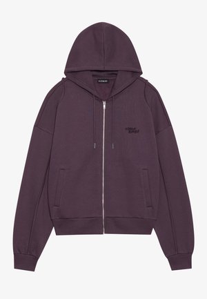 Sudadera con cremallera morada, con capucha, bolsillos frontales, puños acanalados y logo bordado. Hecha de una tela suave y texturizada.