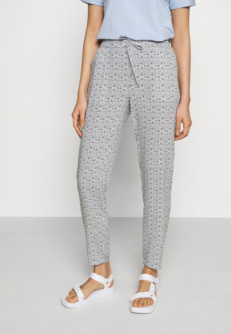 Vzory kalhot v černé a bílé barvě s přiléhavým střihom, páskem na zavazování a zúženými nohavicemi. V kombinaci s bílými sandály na pásečky.