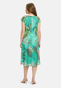 Zielona sukienka w tropikalny wzór z krótkimi, falbaniastymi rękawami, o długości do kolan, wykonana z lekkiego materiału, z bezszwowym projektem z tyłu.