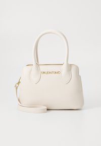 Bolso de mano de cuero beige con dos asas superiores, logotipo dorado y correa de hombro desmontable. Textura suave con bordes redondeados y diseño minimalista.