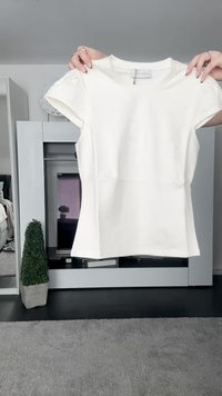 Hvit kortermet tettsittende topp med rund hals, laget av glatt materiale. Har et sømløst design og minimalisme.