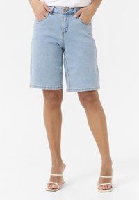 Bermuda shorts in denim blu chiaro con taglio dritto, cinque tasche e dettagli cuciti. I bordi orlati esaltano il design informale.