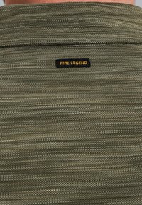Chemise en tricot vert avec un motif texturé, présentant une étiquette noire avec l'inscription "PME LEGEND" en jaune placée au dos.