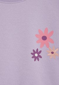 Svetlofialová látka s tromi vyšívanými kvetmi: jedným ružovým s tmavým stredom, jedným tmavofialovým s bielym stredom a jedným béžovým s hnedými akcentmi.