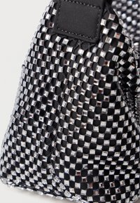 Zwarte handtas met een gestructureerd patroon van vierkante zilveren pailletten. Kenmerken zijn een soepele stoffen basis en een rechthoekige flap aan de zijkant.