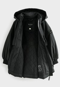 Veste noire matelassée avec capuche, dotée de poignets élastiques, d'une étiquette intérieure et d'un extérieur lisse. La doublure intérieure est également noire.