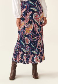 Fustă maxi florală de culoare albastră închisă, cu modele colorate de paisley și flori. Plisaje acordeon, talie elastică. Asortată cu boots maro.