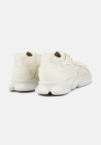 White sneakers featuring a mix of smooth and perforated materials, rounded heel, and a textured sole for grip and comfort.
