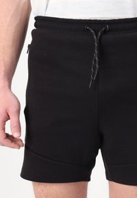 Black athletic shorts made of cotton blend fabric, featuring an elastic waistband with drawstring and side zip pockets.