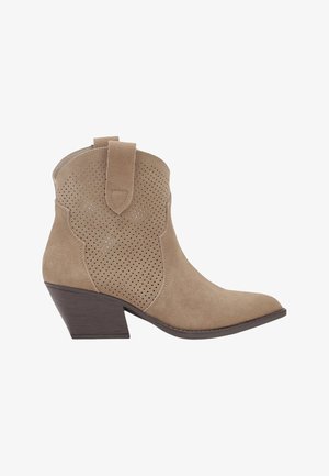 Bottine beige en daim avec côtés perforés, bout pointu, languette d'enfilage et talon bloc de couleur marron foncé.