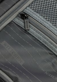 Šedý textilní interiér s kapsou na zip. Síťovaná část a brandovaný zatahovací prvek se zřetelným nápisem "WITTCHEN". Prošité detaily po celém povrchu.