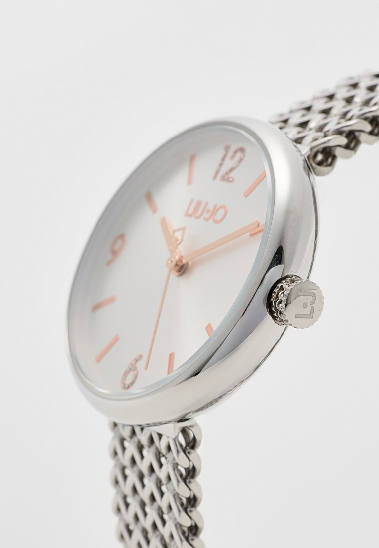 Zilveren polshorloge met een mesh band, witte wijzerplaat, roségouden accenten en duidelijke cijfermarkeringen op 12, 6 en 9 uur.