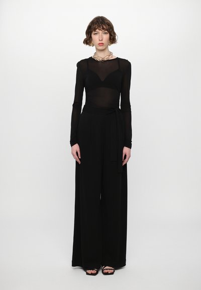 Black two-piece outfit featuring a sheer long-sleeve top with a V-neck and high-waisted wide-leg pants, finished with a tied belt.