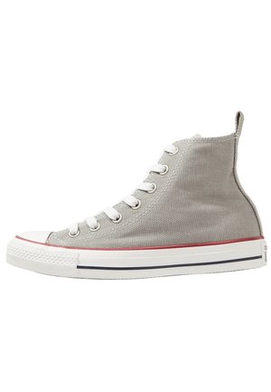 Hellgrauer Canvas-Sneaker mit hohem Schaft, weißen Schnürsenkeln, Gummikappe vorne und weißer Sohle mit roten und schwarzen Streifen.