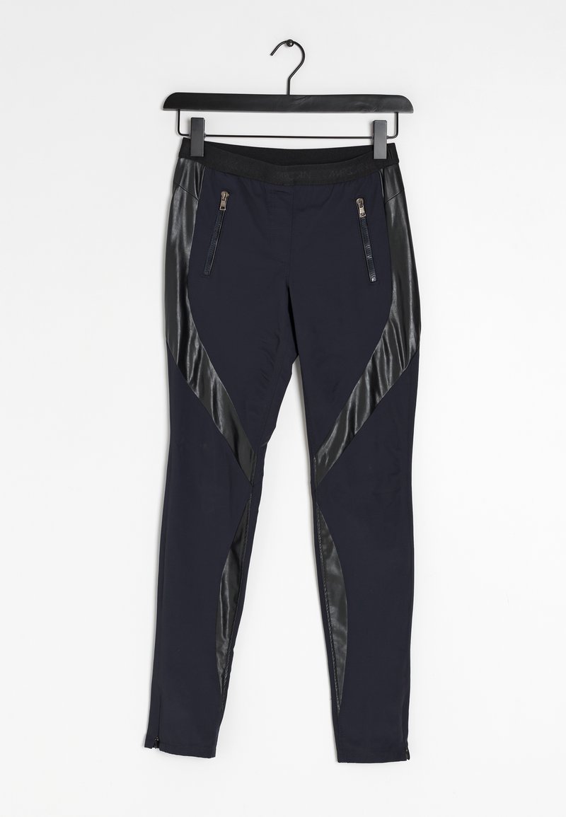 Leggings bleu marine avec panneaux diagonaux en similicuir noir, taille élastique, poches avant zippées et fermetures éclair aux chevilles, suspendus sur un cintre noir.