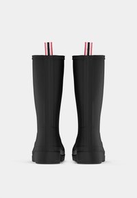 Fekete gumibokák, térd fölé érő, textúrával ellátott felülettel és lapos talppal, piros-fehér csíkos húzófüllel a tetején.
