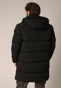 Zwarte pufferjas met een capuchon, voorzien van een gecapitonneerd ontwerp, verticale stiksels en een middellange pasvorm. Gladde, matte stoftekstuur.