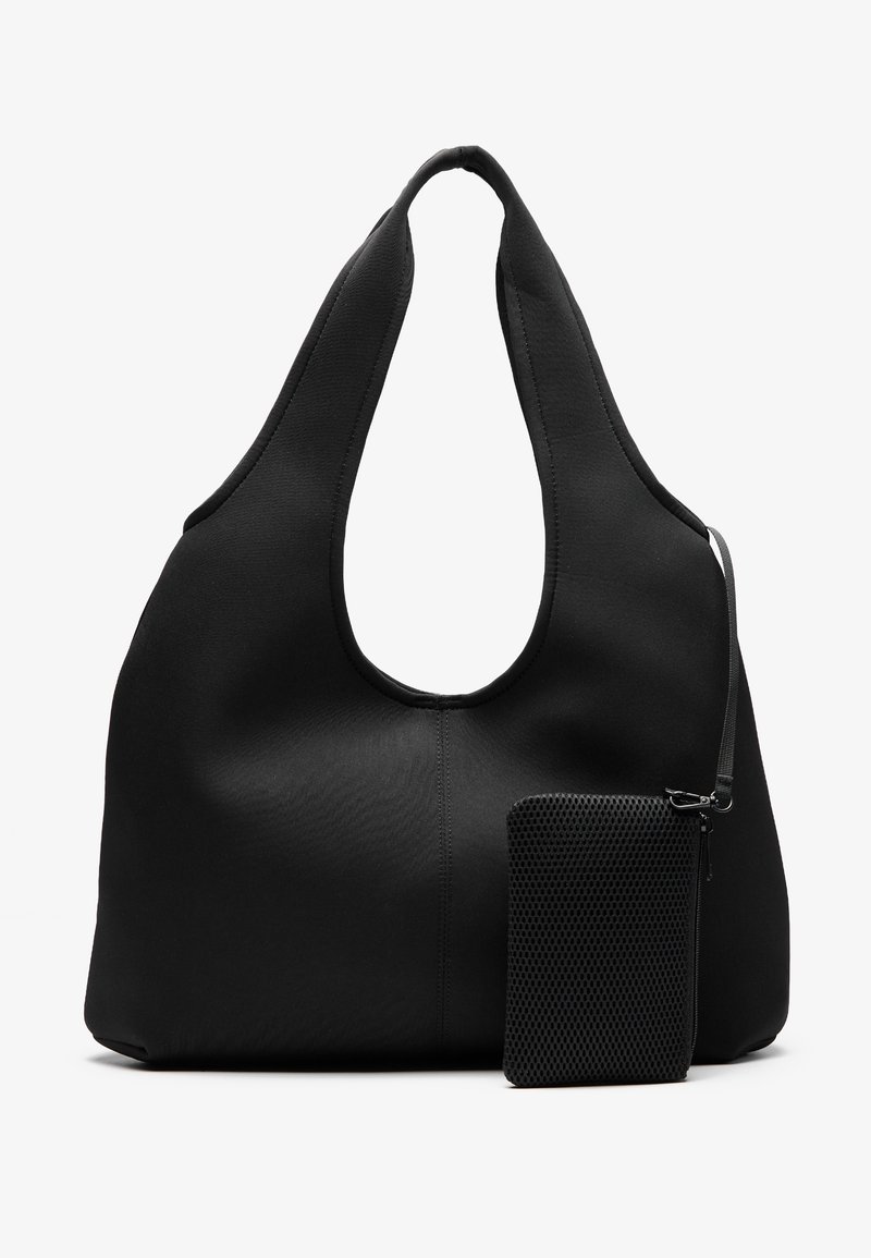 Grand sac fourre-tout en tissu noir doux avec de larges anses et une petite pochette zippée texturée attachée par une sangle sur fond blanc.