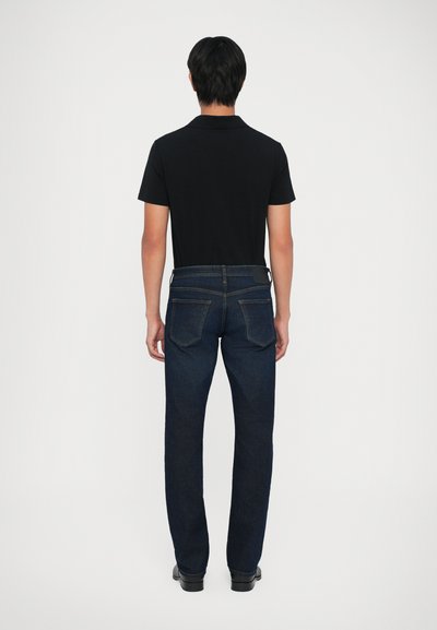 Temno modri jeans z ravno nogavico in dvema zadnjima žepoma, v kombinaciji s črno majico s kratkimi rokavi.