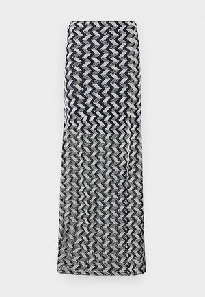 Tissu tricoté plié à motif zigzag noir et blanc, présenté à plat sur un fond gris clair.