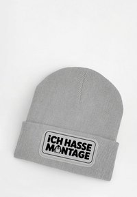 Light gray knit beanie with folded cuff, featuring a patch with black text "ICH HASSE MONTAGE" and a small penguin graphic.