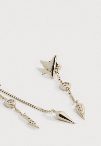 Srebrna naušnica s klinčićem s privjescima u obliku zvijezde, geometrijskih i okruglih privjesaka na nježnoj lancu na bijeloj pozadini.