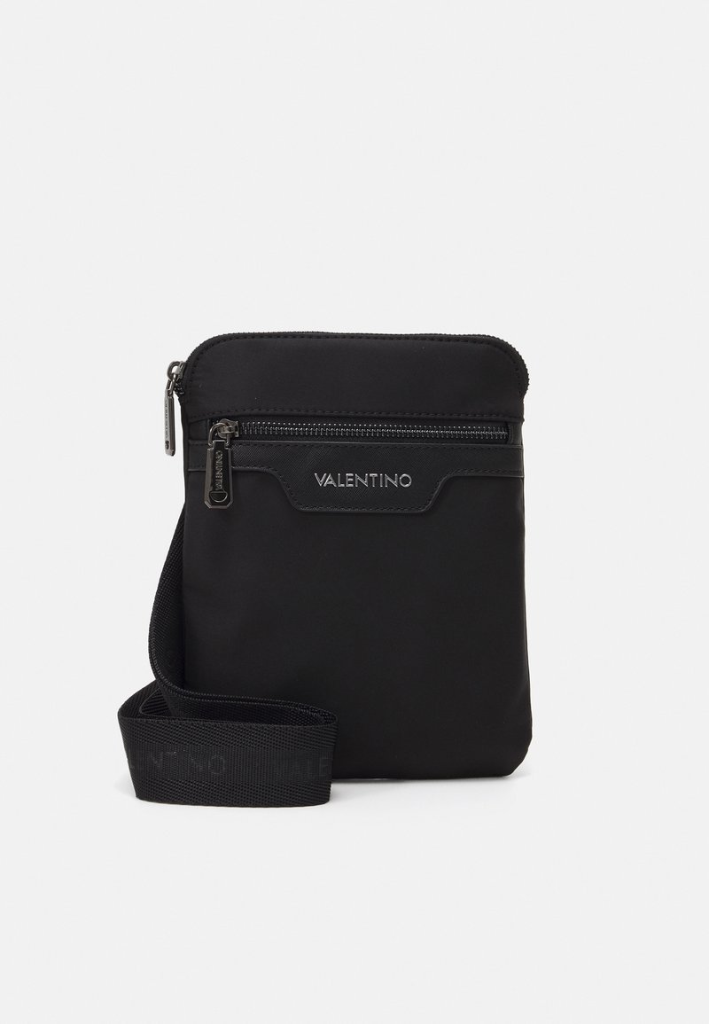 Černá nylonová crossbody taška se zipovým uzávěrem, přední kapsou a nastavitelným popruhem. Disponuje hladkou texturou a stříbrným kováním.