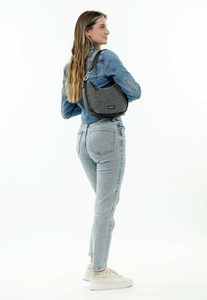 Schwarz-weiße gestreifte Handtasche mit Lederelementen, hellblaue Jeansjacke, helle Jeans und weiße Sneaker. Gerade Passform, minimale Details.