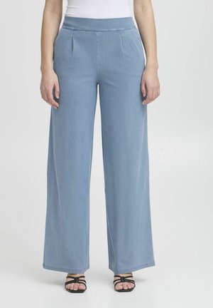 Vaaleansiniset leveät housut korkealla vyötäröllä, joissa on etutaitokset ja sileä denim-kangas. Yhdistetty mustiin nauhakenkiin.