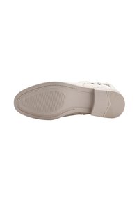 Suela de zapato de goma beige con un dibujo en relieve, que presenta un acabado texturizado y un ligero tacón. Bordes suaves y forma rectangular.