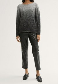 Maglione a maglia ombre in grigio e nero con maniche lunghe e colletto a coste, abbinato a pantaloni neri effetto pelle e mocassini.