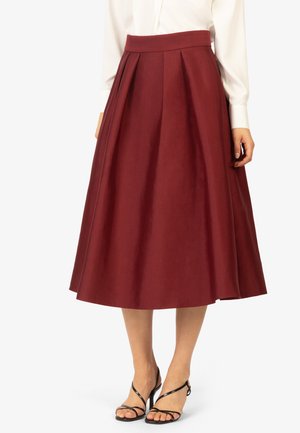 Gonna midi bordeaux con pieghe, realizzata in tessuto liscio. Styling con un cintura aderente, abbinata a sandali neri con cinturini.