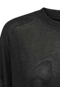 Top nero lavorato a maglia con scollo rotondo, texture morbida e vestibilità ampia. Un leggero lucido ne esalta il fascino visivo.