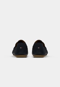 Marineblå læder loafers med lav profil og stikninger. Har et lille logo i rød, hvid og blå på hælen.