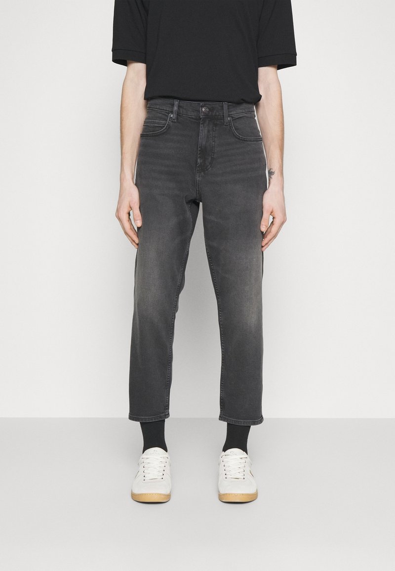 Jeans in denim grigio con una vestibilità regolare, lunghezza cropped e leggera sbiaditura. Abbinati a sneakers bianche e calzini neri alla caviglia.