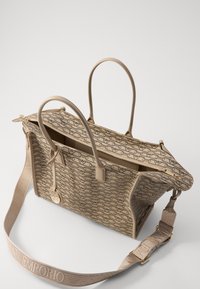 Beige tote-väska med mönstrad utsida, dubbla handtag, justerbar axelrem och en dragkedja huvudfack. Detaljer i guld-ton.