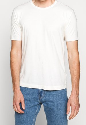 Weißes Baumwoll-T-Shirt mit Rundhalsausschnitt und kurzen Ärmeln, klassischem Schnitt und glatter Textur, kombiniert mit blauen Jeans.