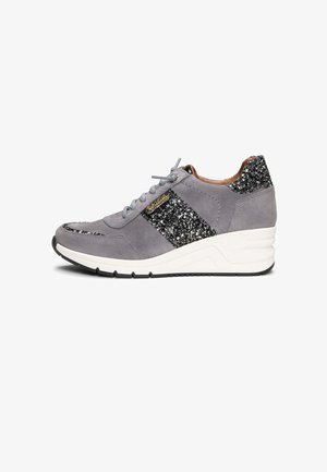 Zapatilla de gamuza gris con acentos de purpurina negra, suela blanca, cordones en la parte delantera y tacón cuña, vista lateral sobre fondo blanco.