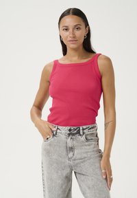 Canotta aderente a costine di un vivace rosa con scollo quadrato. Abbinata a jeans chiari a vita alta, leggermente scuciti.