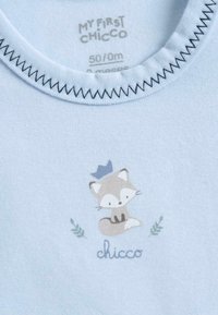 Body en coton bleu clair avec un col rond ; arbore une illustration imprimée d'un renard avec une couronne et des feuilles, avec le texte "chicco" en dessous.