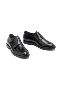 Zwarte leren schoenen met een gladde afwerking, voorzien van een dubbele gesp-sluiting en een lage rubberen zool voor comfort.