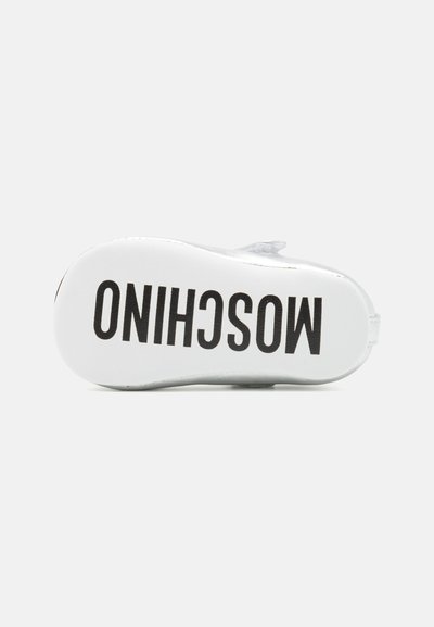 Suela blanca de zapato con el texto "MOSCHINO" en negro. Acabado suave; forma redondeada; diseño simple sin patrones o acentos adicionales.