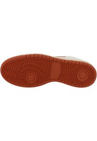 Shoe outsole with a rubber midsole, featuring a zigzag pattern in reddish-brown and circular accents. Smooth, durable texture.
