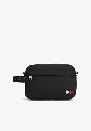 Sort rektangulær toilettaske med frontlynlåslomme, sidelomme med tekst og Tommy Jeans logo patch i nederste højre hjørne.