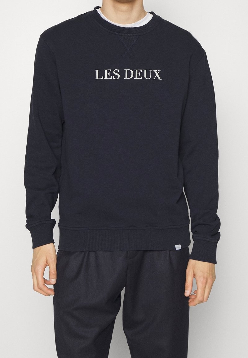 Sudadera azul marino de hombre con la inscripción "LES DEUX" en gris claro. Cuello redondo, puños y dobladillo acanalados, confeccionada con una mezcla de algodón suave.