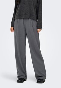 Calças de perna larga em tecido cinza claro, com textura suave e corte descontraído. Combinadas com um top de manga comprida escuro e folgado.