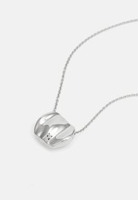 Silberne Halskette mit einem geschwungenen, skulpturalen Anhänger mit polierter Oberfläche. Die Kette ist zart und wirkt gewoben.