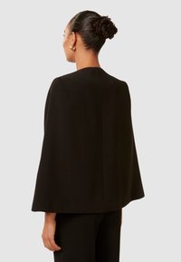 Schwarzer Umhang mit glatter Textur, weiten Ärmeln und gerader Rückennaht. Das Design ist minimalistisch, ohne sichtbare Verschlüsse oder Verzierungen.