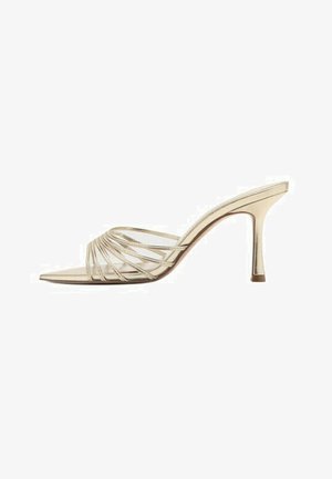 Sandalia mule de tacón alto en oro con finas correas curvas sobre el dedo del pie descubierto y un tacón delgado y afilado.